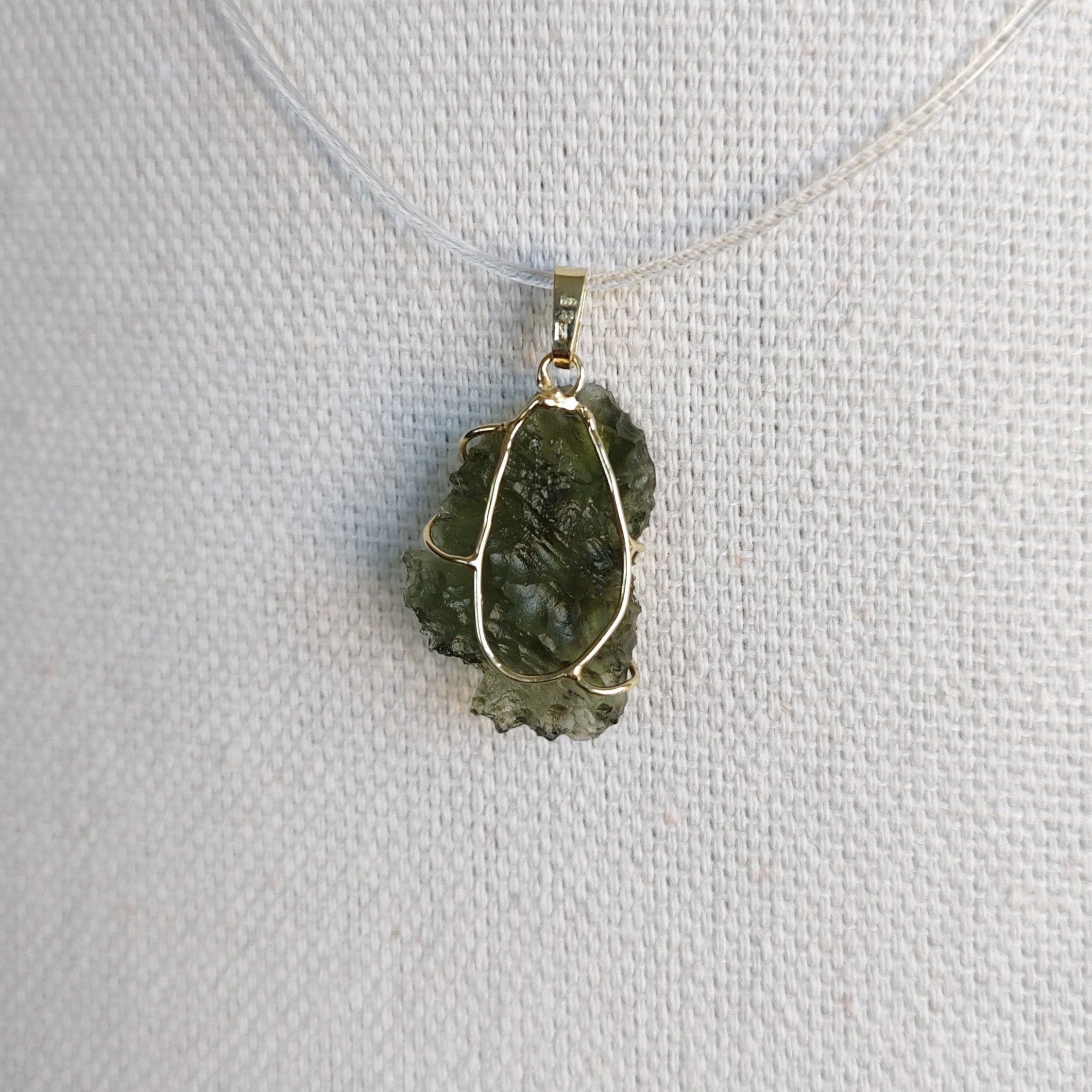 Back view of a raw Besednice moldavite pendant set in 14kt yellow gold.