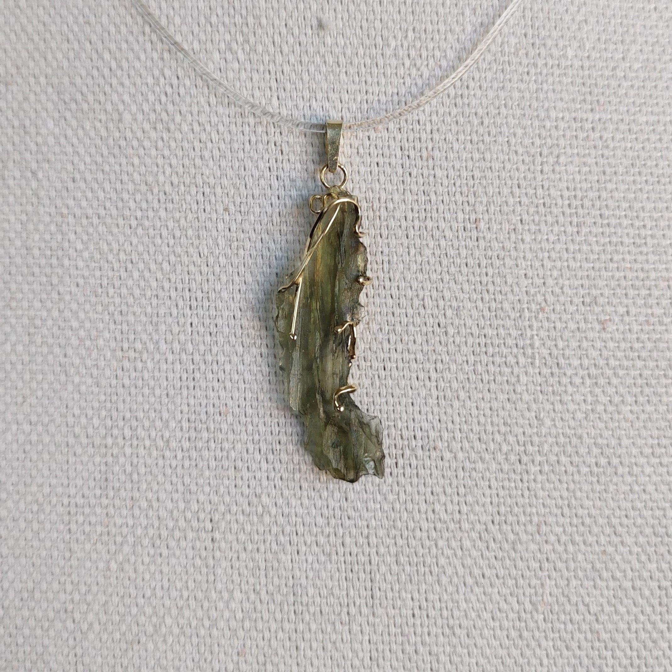 Front view of a raw Besednice moldavite pendant set in 14kt yellow gold.