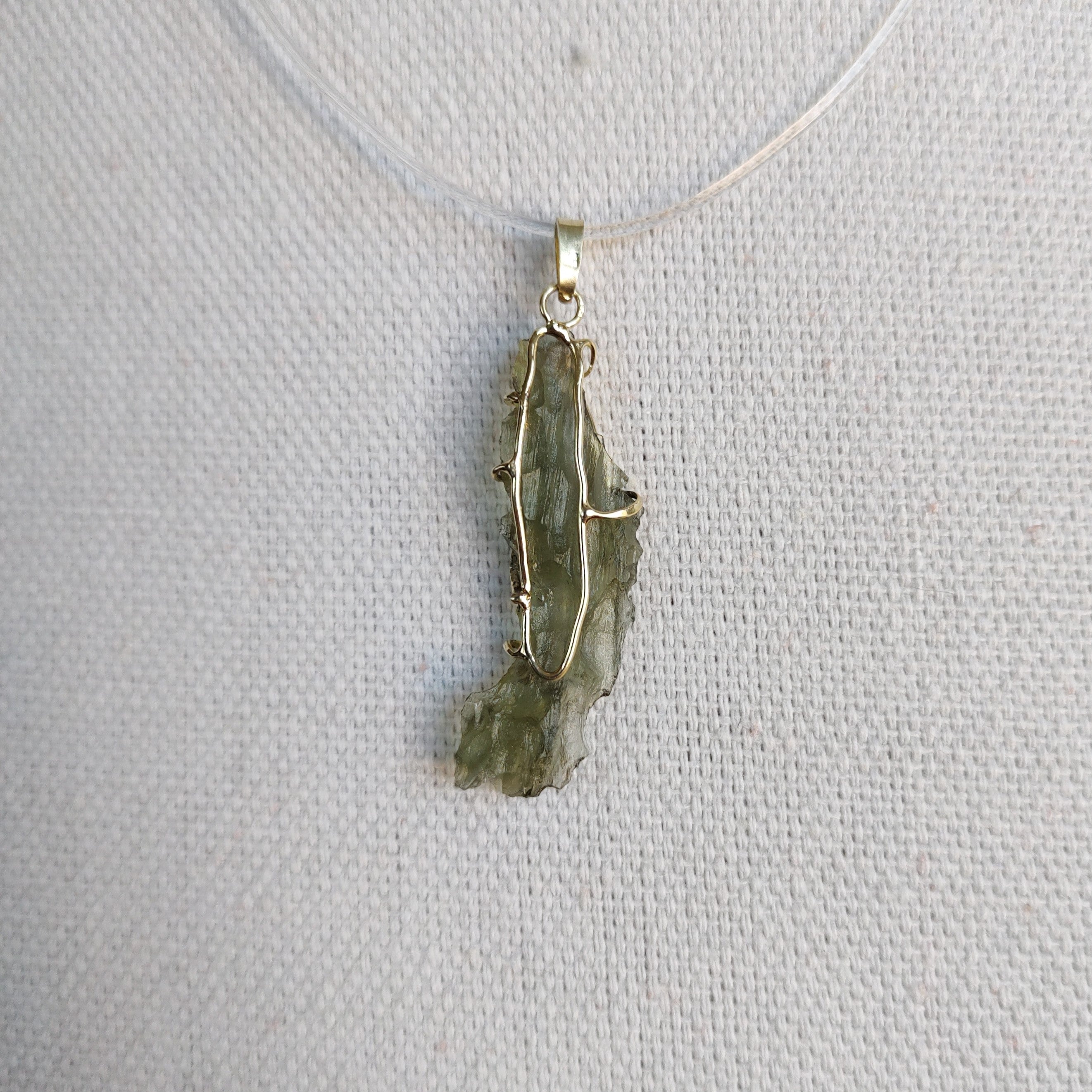 Back view of a raw Besednice moldavite pendant set in 14kt yellow gold.