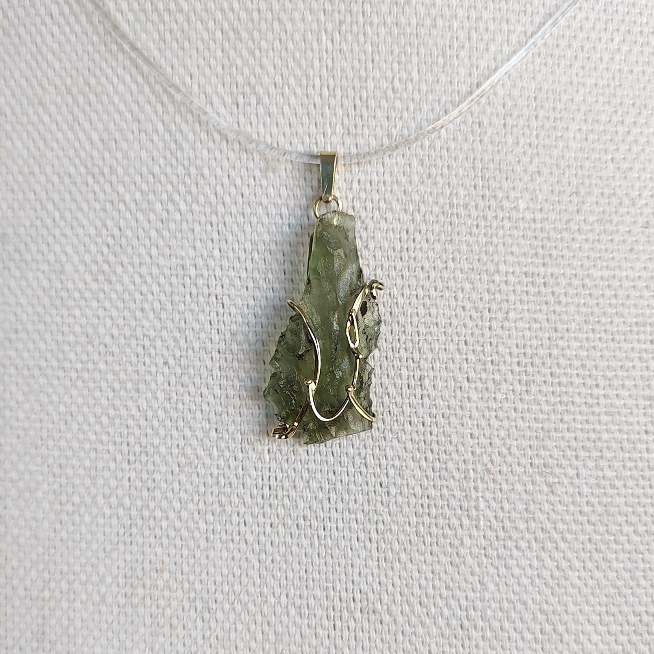 Front view of a raw Besednice moldavite pendant set in 14kt yellow gold.