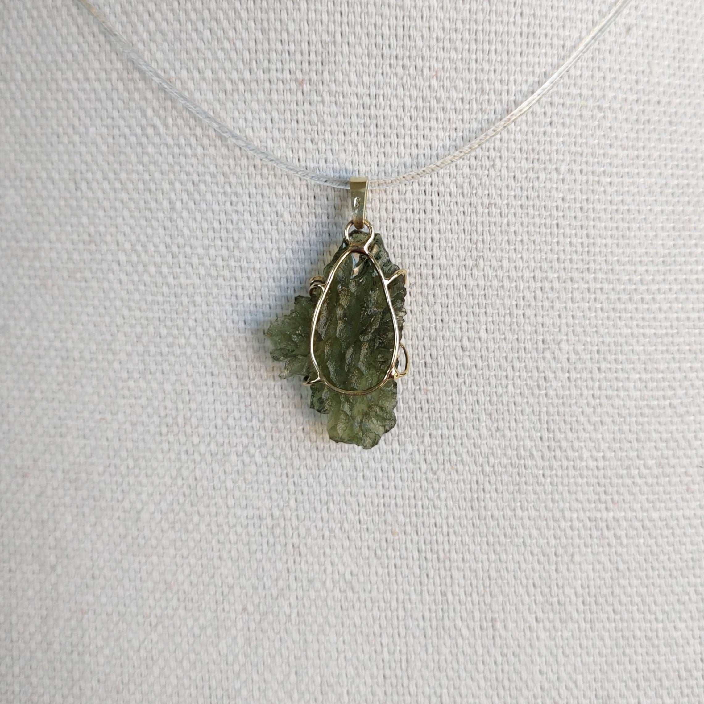 Back view of a raw Besednice moldavite pendant set in 14kt yellow gold.