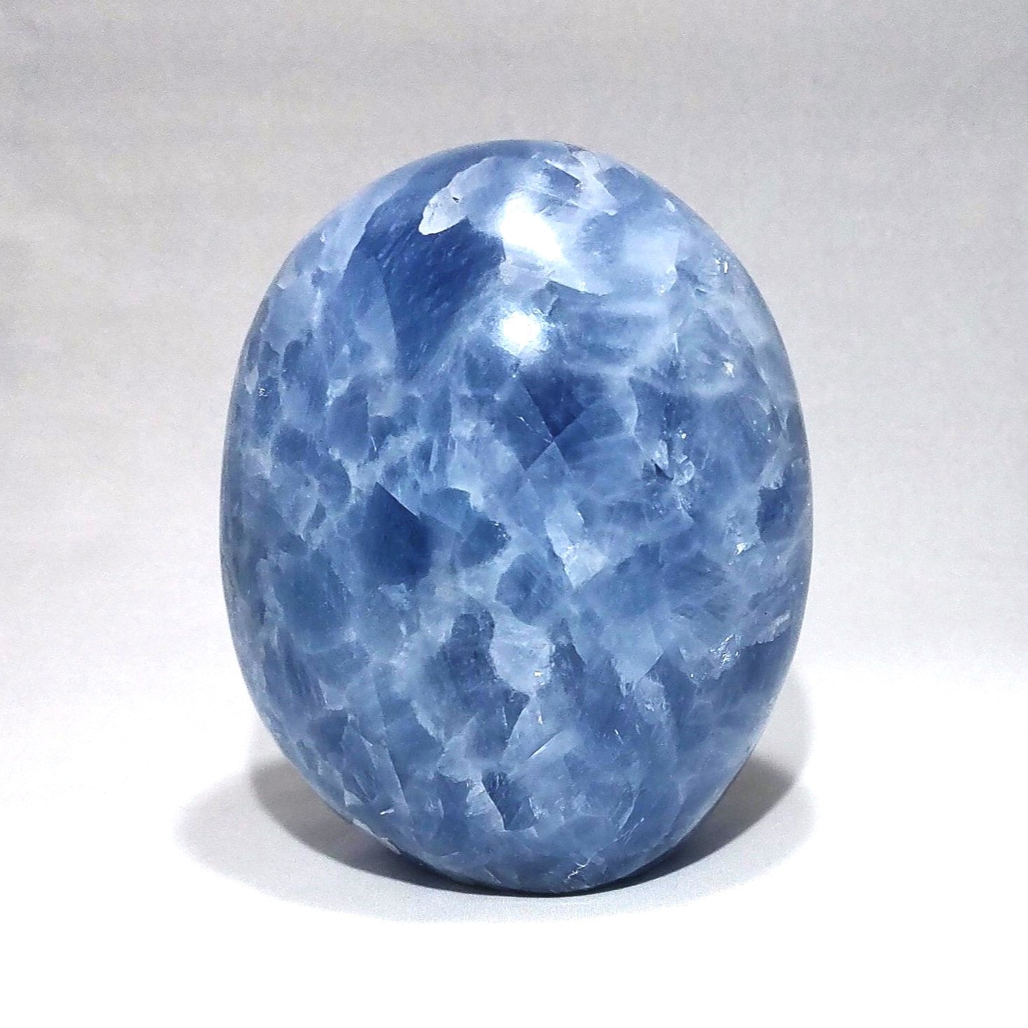 A blue calcite freeform carving is shown against a white background.