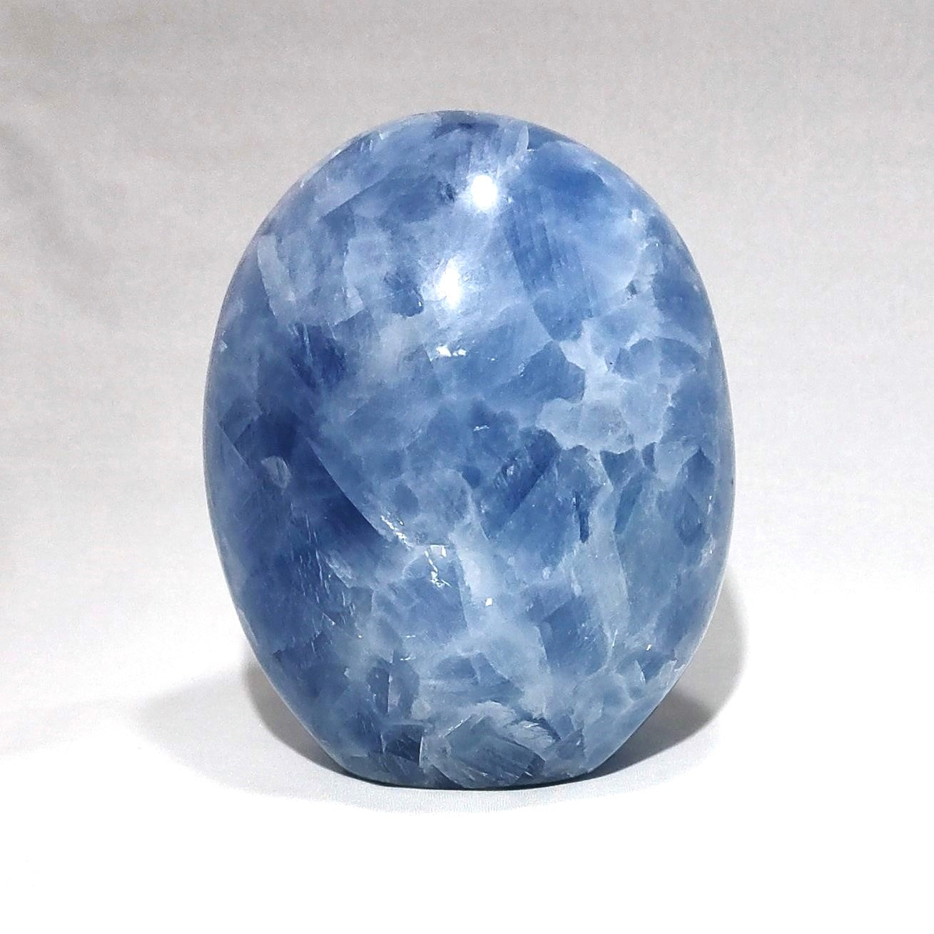 A blue calcite freeform carving is shown against a white background.