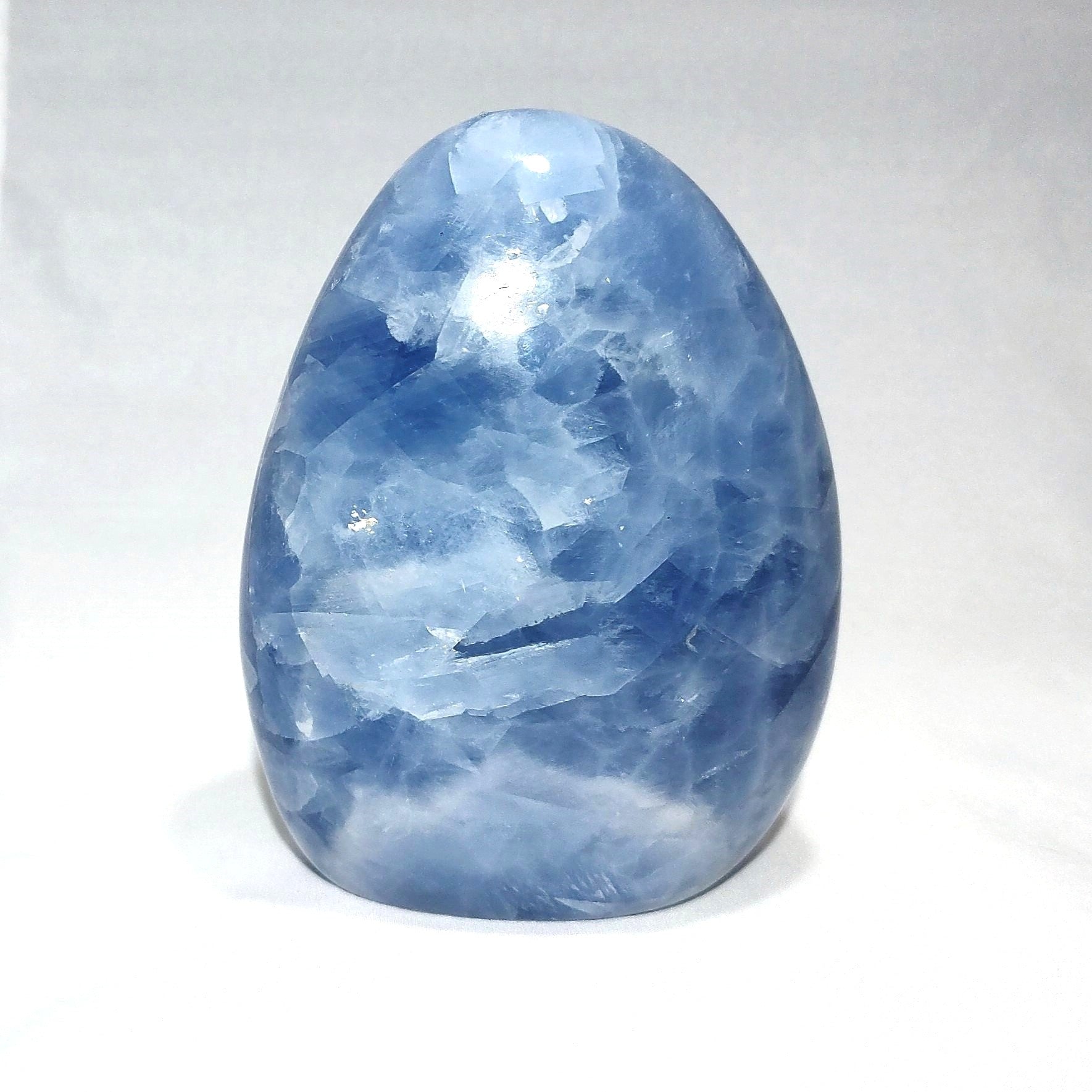 A blue calcite freeform carving is shown against a white background.