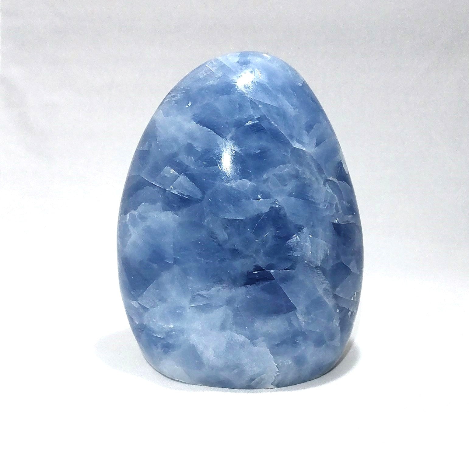 A blue calcite freeform carving is shown against a white background.