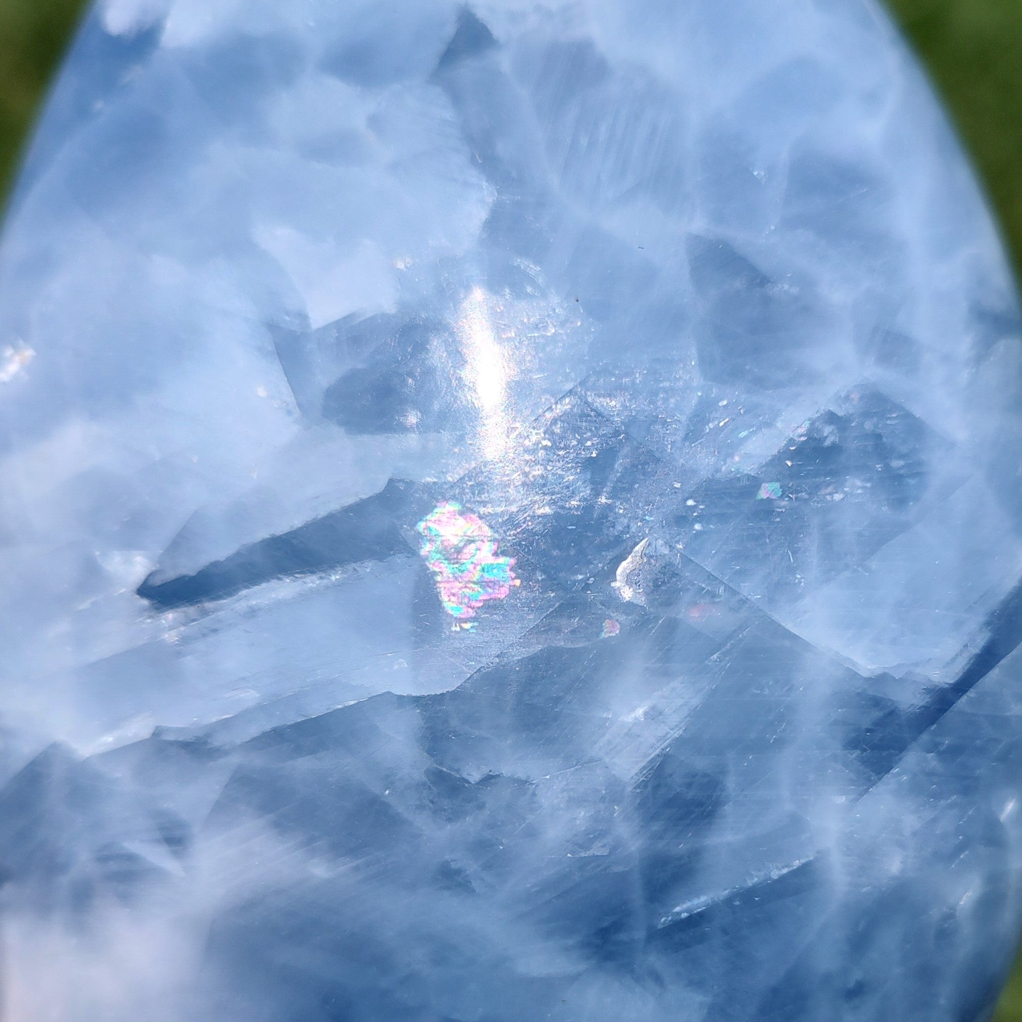 Closeup of blue calcite freeform carving, with sunlight creating a rainbow effect.