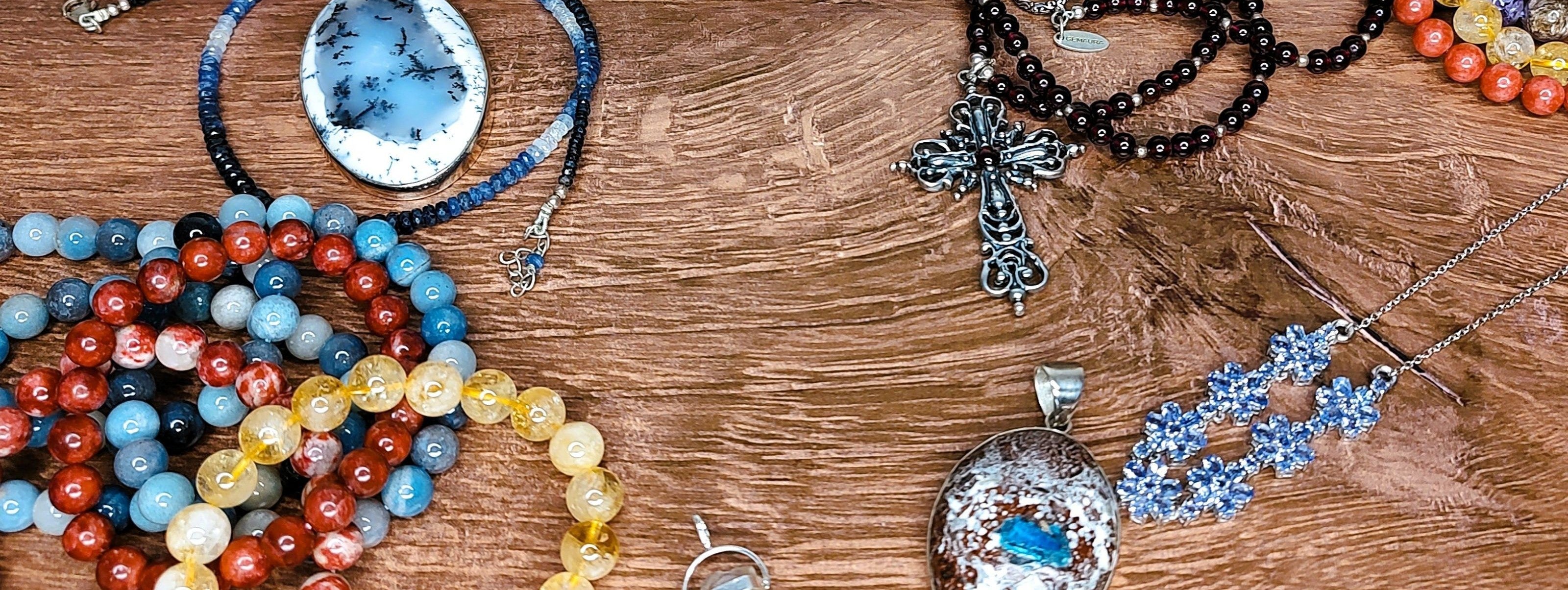 Collection of necklaces, pendants and bracelets on a wooden surface.