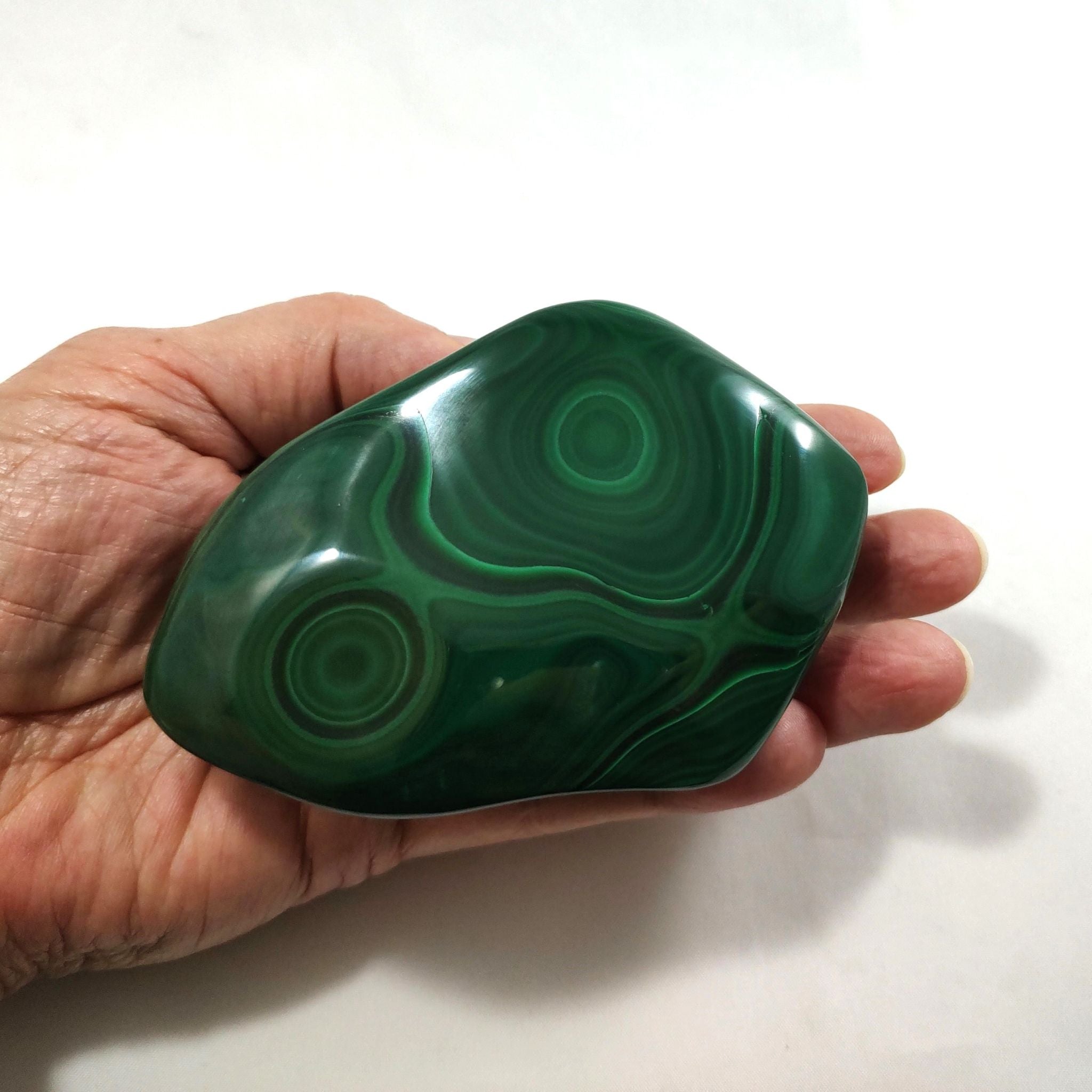 Hand holding a malachite crystal freeform carving