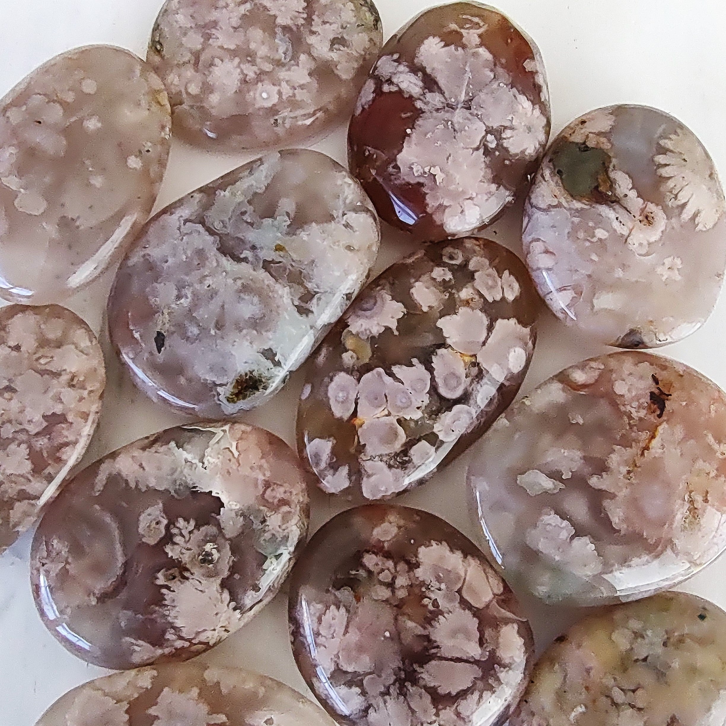 Collection of flower agate palm stones on a white surface.