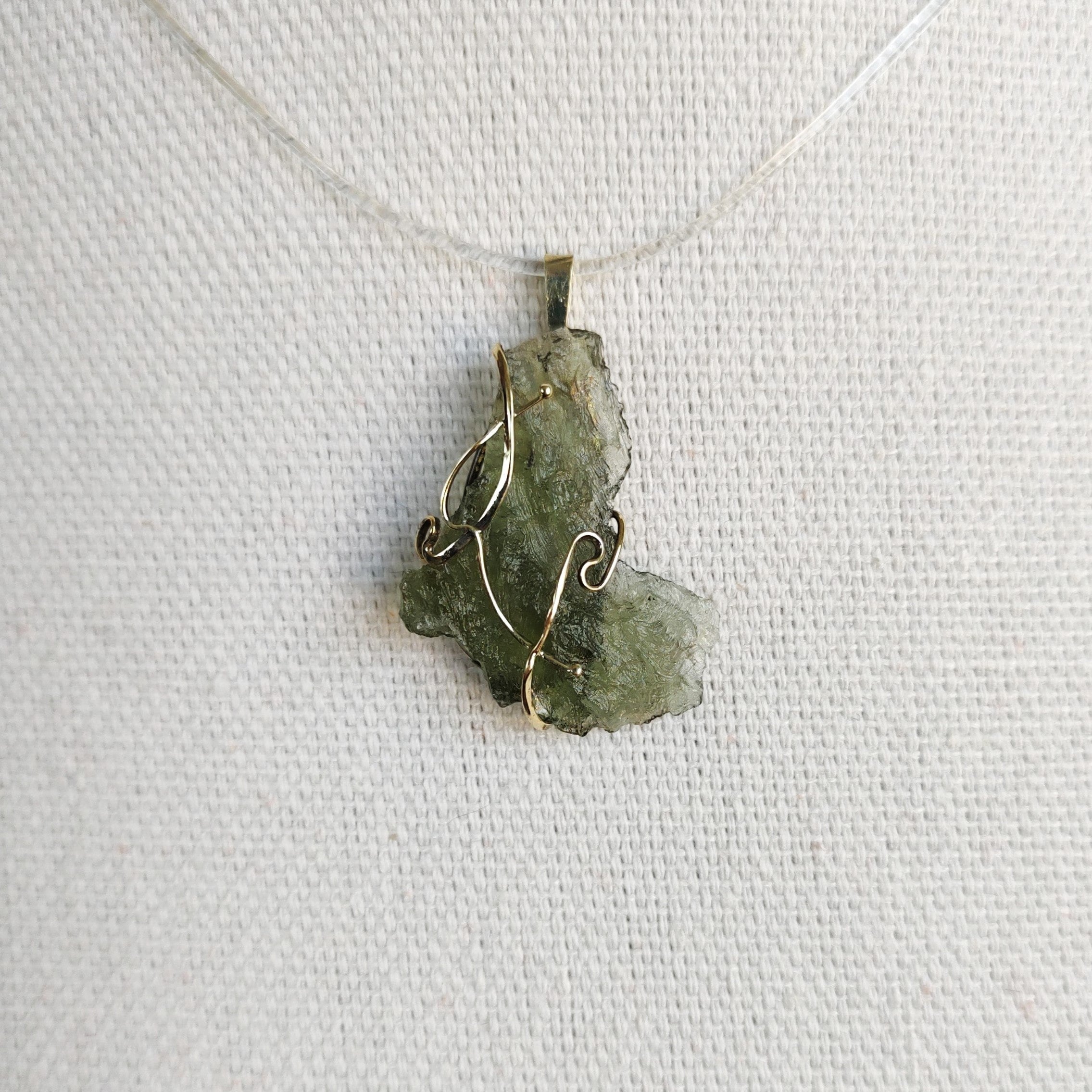 Front view of a raw Besednice moldavite pendant set in 14kt yellow gold. 
