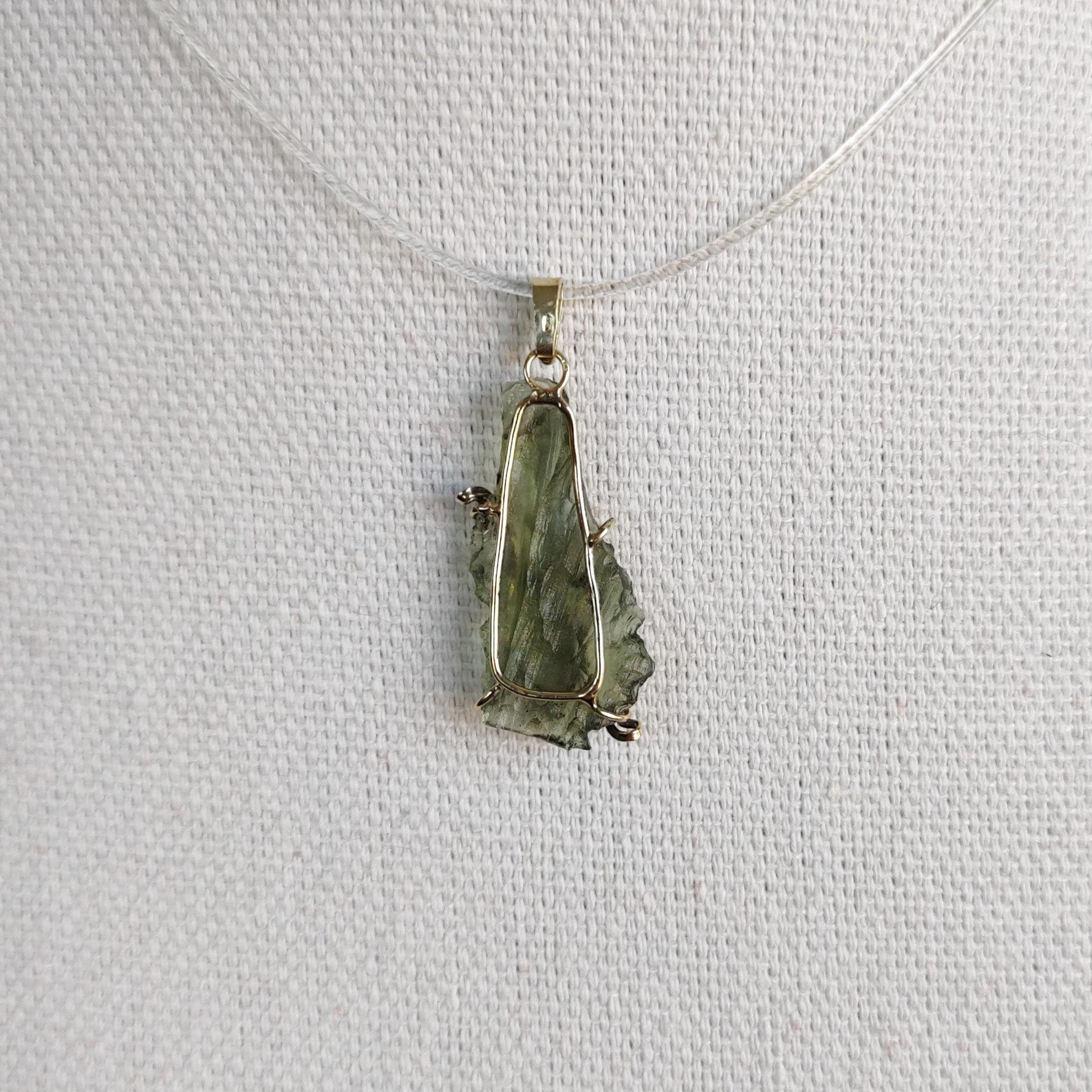 Back view of a raw Besednice moldavite pendant set in 14kt yellow gold.