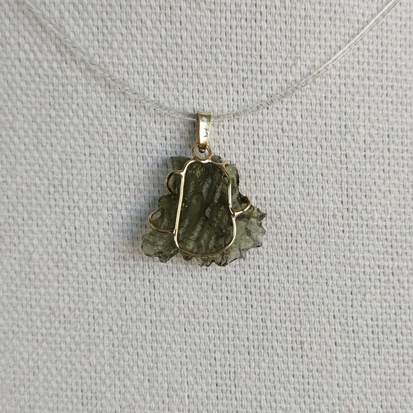 Back view of a raw Besednice moldavite pendant set in 14kt yellow gold.