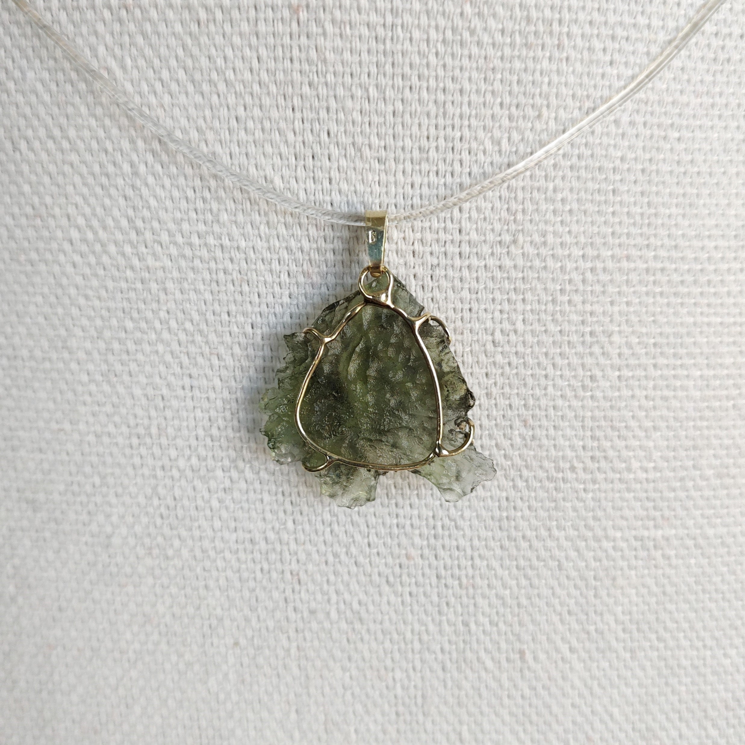 Back view of a raw Besednice moldavite pendant set in 14kt yellow gold.