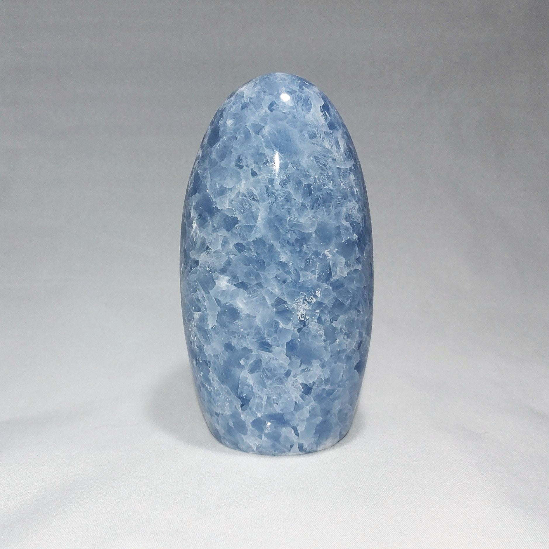 A blue calcite freeform carving is shown against a white background.