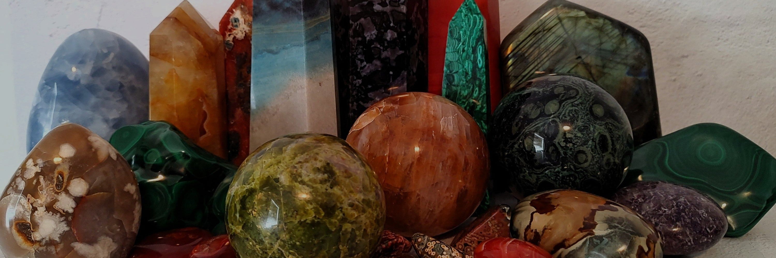 Collection of various crystals and stones on a light wooden surface.