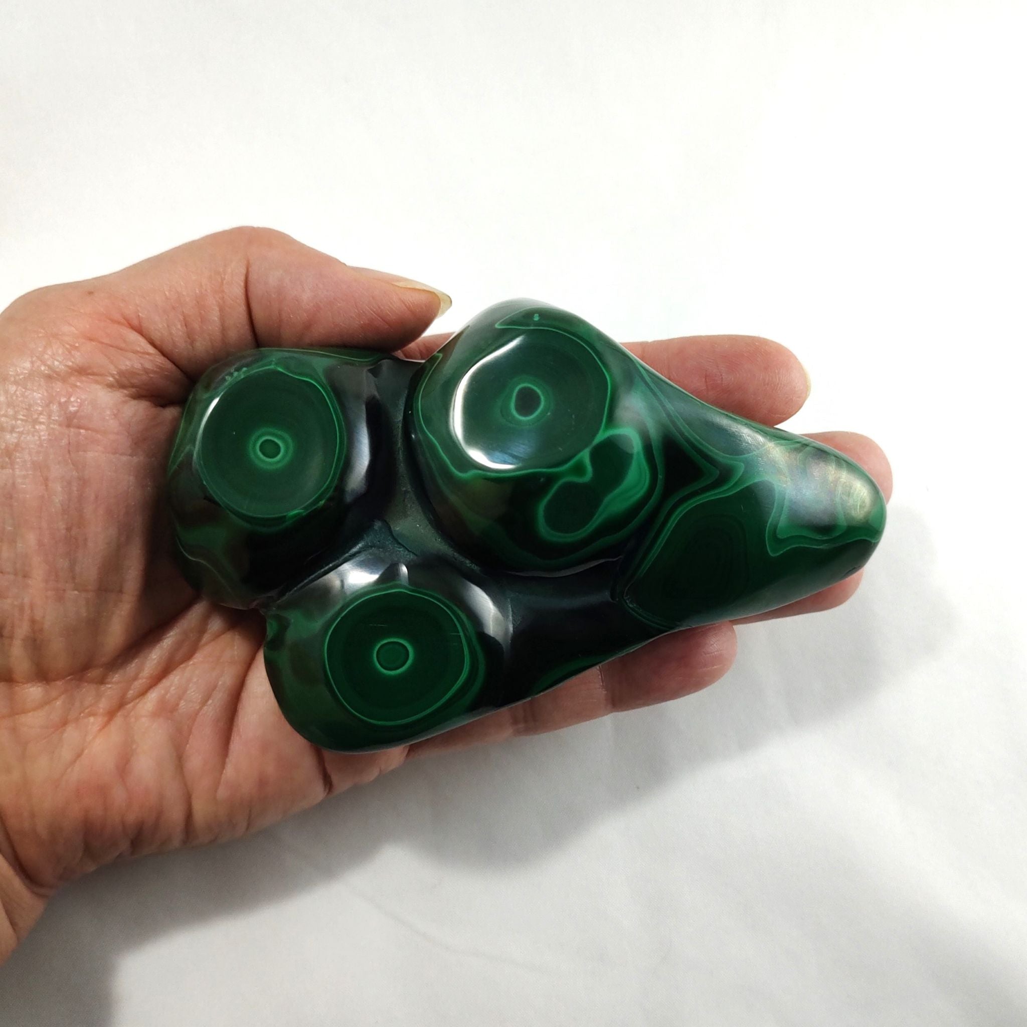 Hand holding a malachite crystal freeform carving