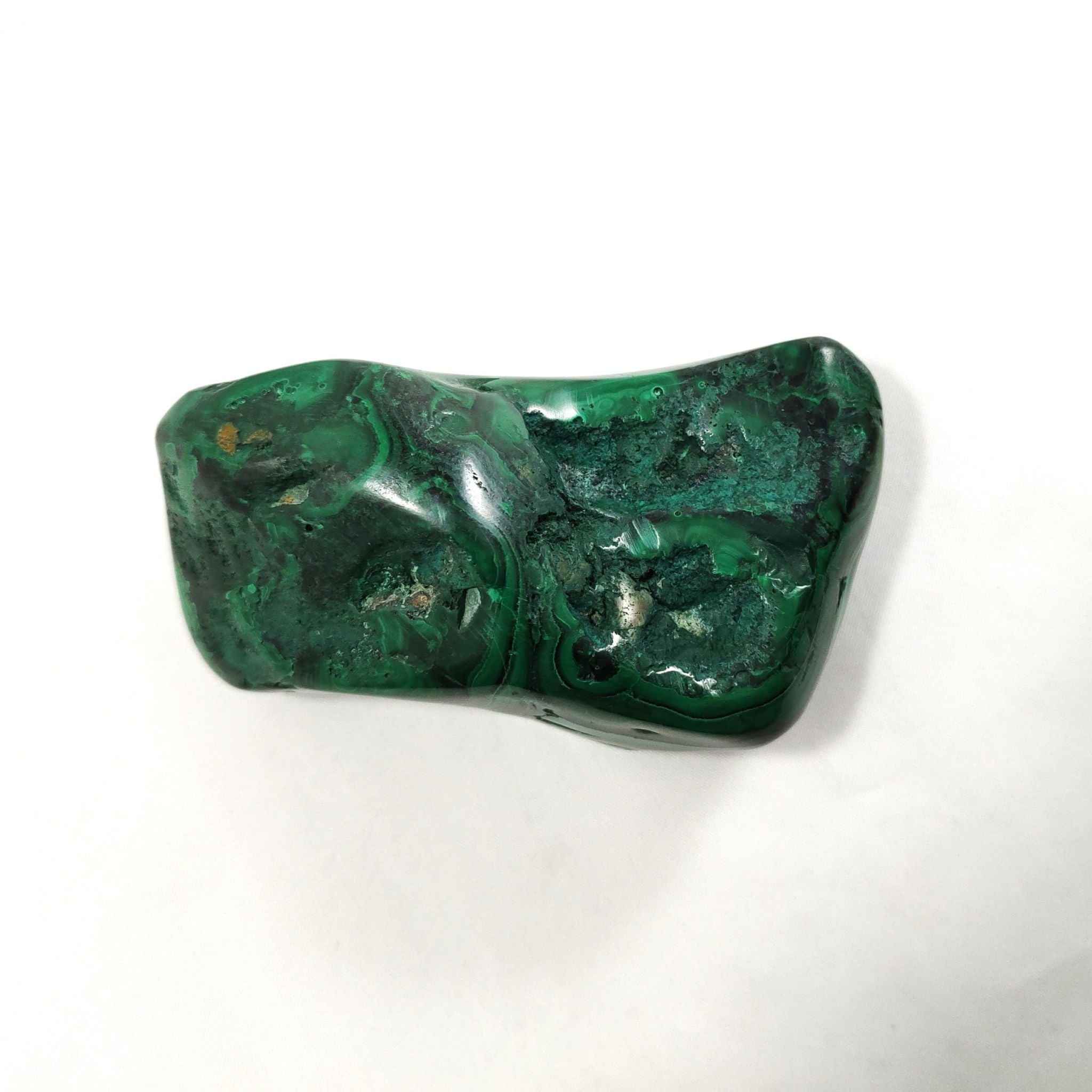 Back of malachite crystal freeform carving on a white background