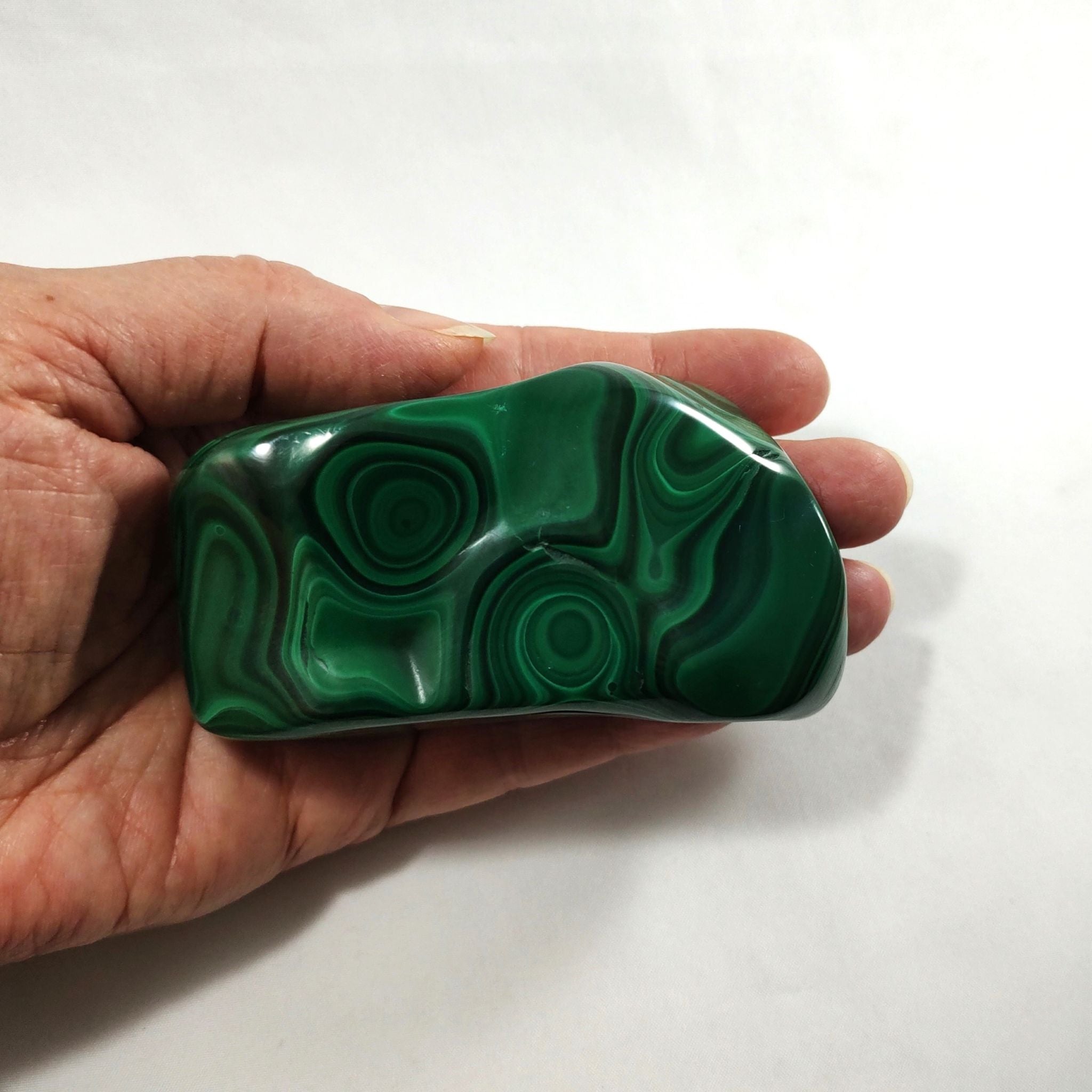 Hand holding a malachite crystal freeform carving